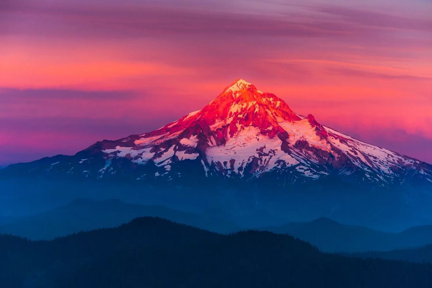 a snow covered mountain is shown at sunset